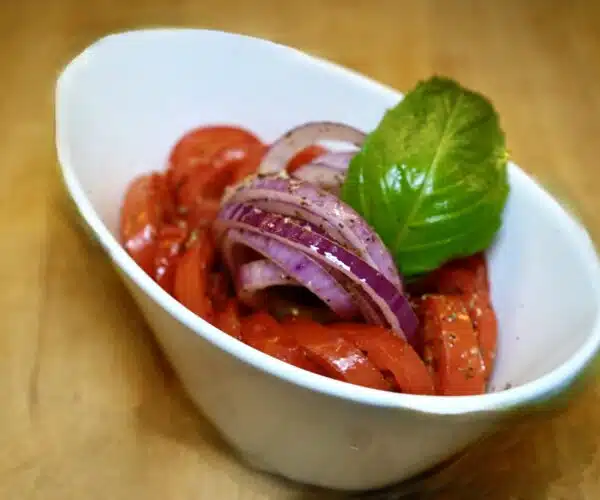 red tomatoes and red onions with a leave of basil